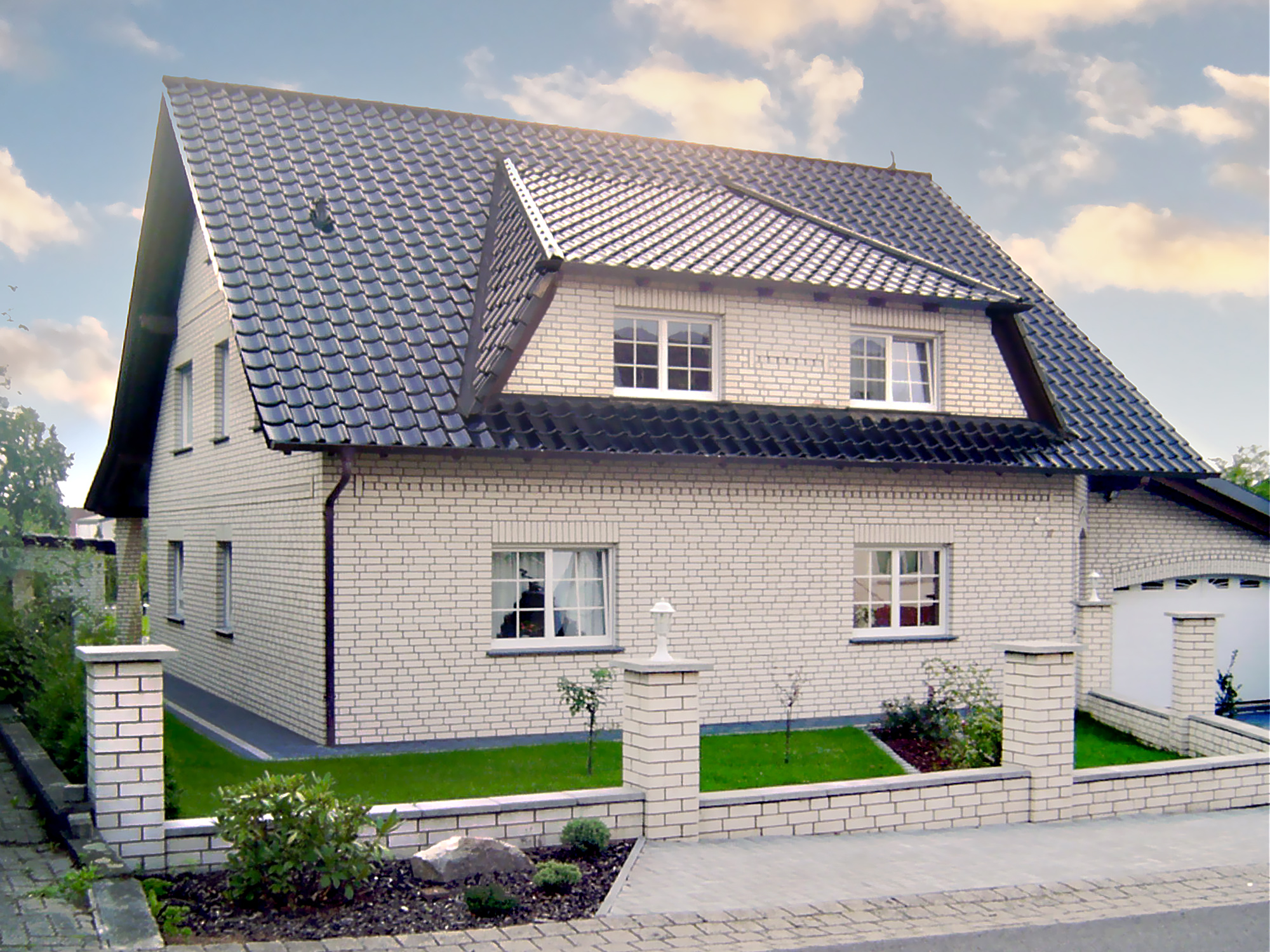 Einfamilienhaus mit Garage und hellem Verblendmauerwerk Zweifamilienhaus mit heller Klinkerfassade, dunklem Satteldach, gepflegtem Vorgarten und Einfahrt mit Garage.