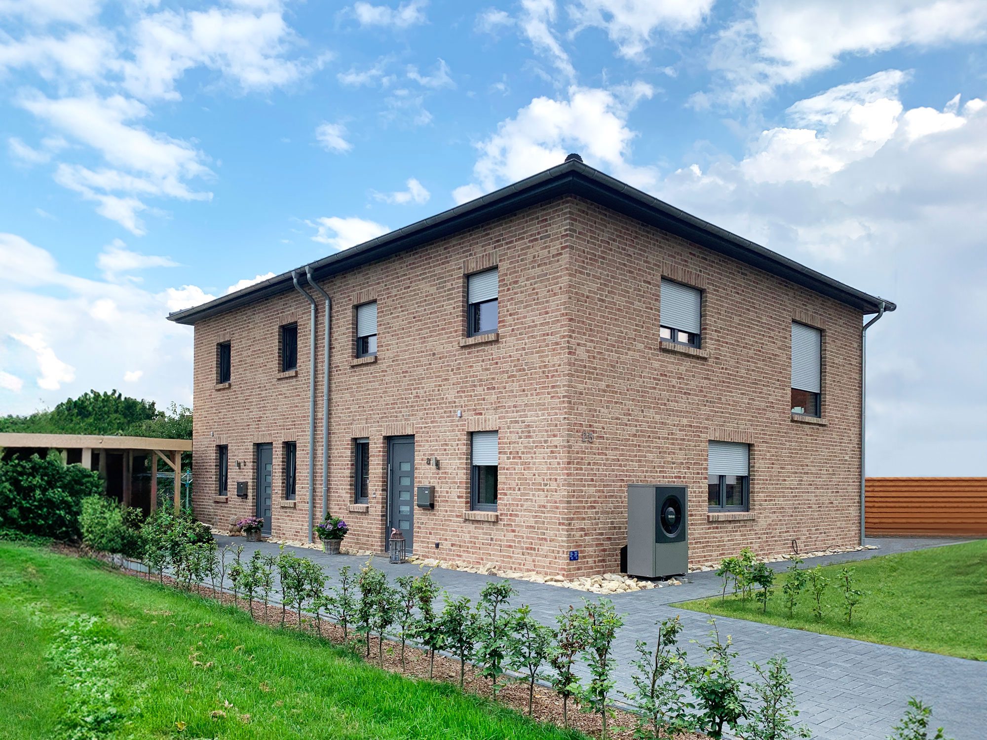 Modernes Doppelhaus mit roter Klinkerfassade und Wärmepumpe Modernes zweigeschossiges Doppelhaus mit roter Klinkerfassade, anthrazitfarbenen Türen, Wärmepumpe und gepflegtem Vorgarten.